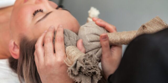 Une praticienne enveloppe doucement une femme dans un tissu rebozo pour un rituel de bercements.
